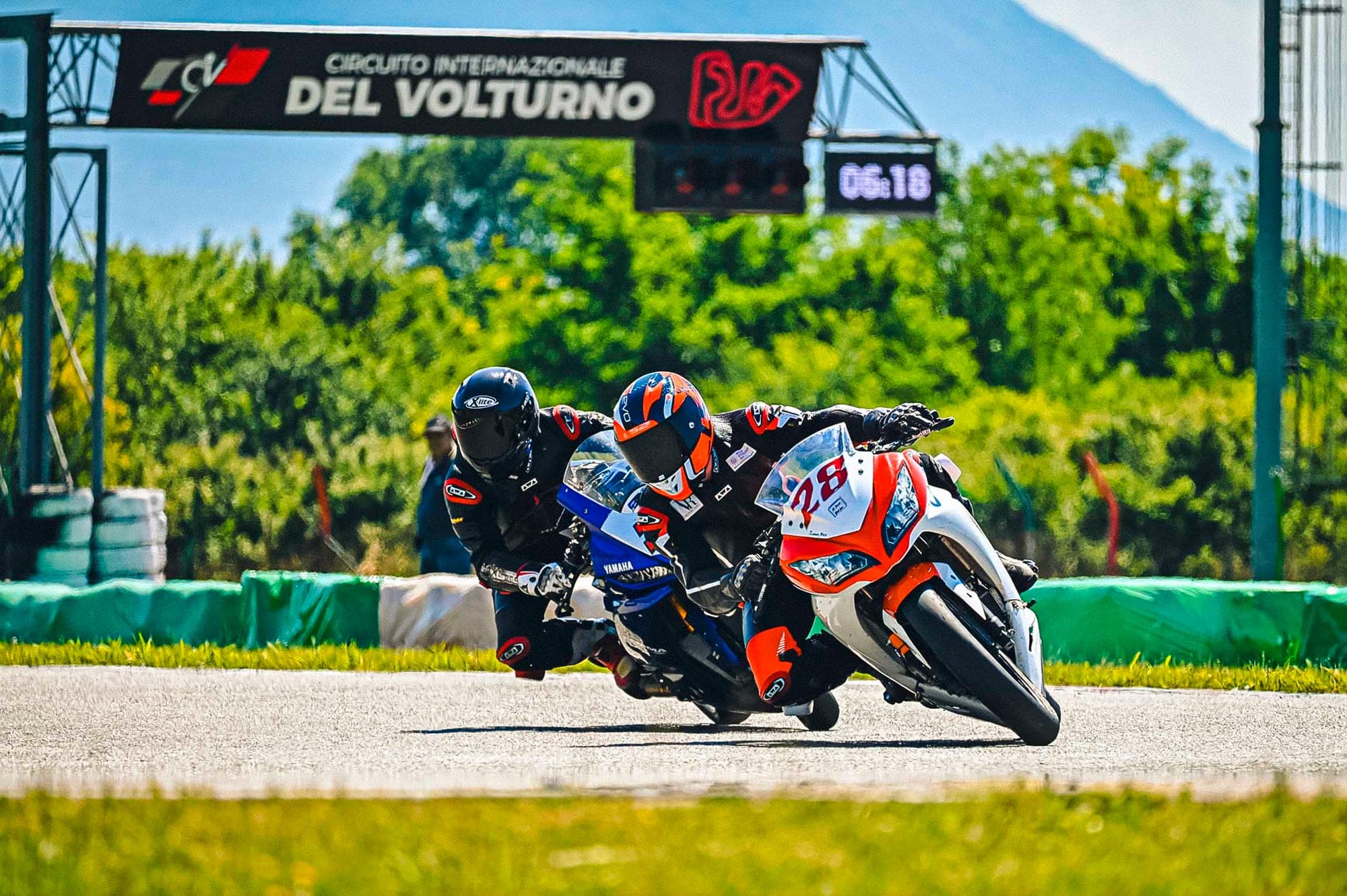 Pilota in piega con la moto numero 28 sotto il portale del circuito